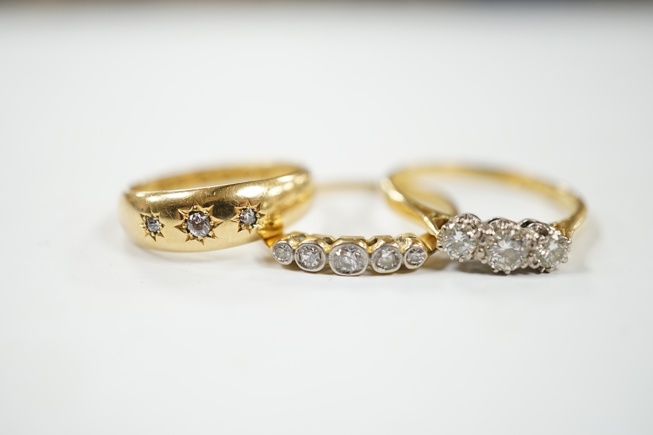 A late Victorian 18ct gold and gypsy set three stone diamond chip ring and two other 18ct and diamond set rings, three stone and five stone